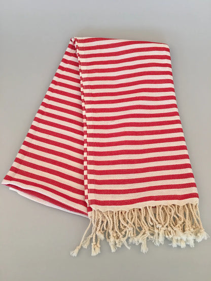 Red and white striped Turkish towel with fringed edges, folded on a light gray background.