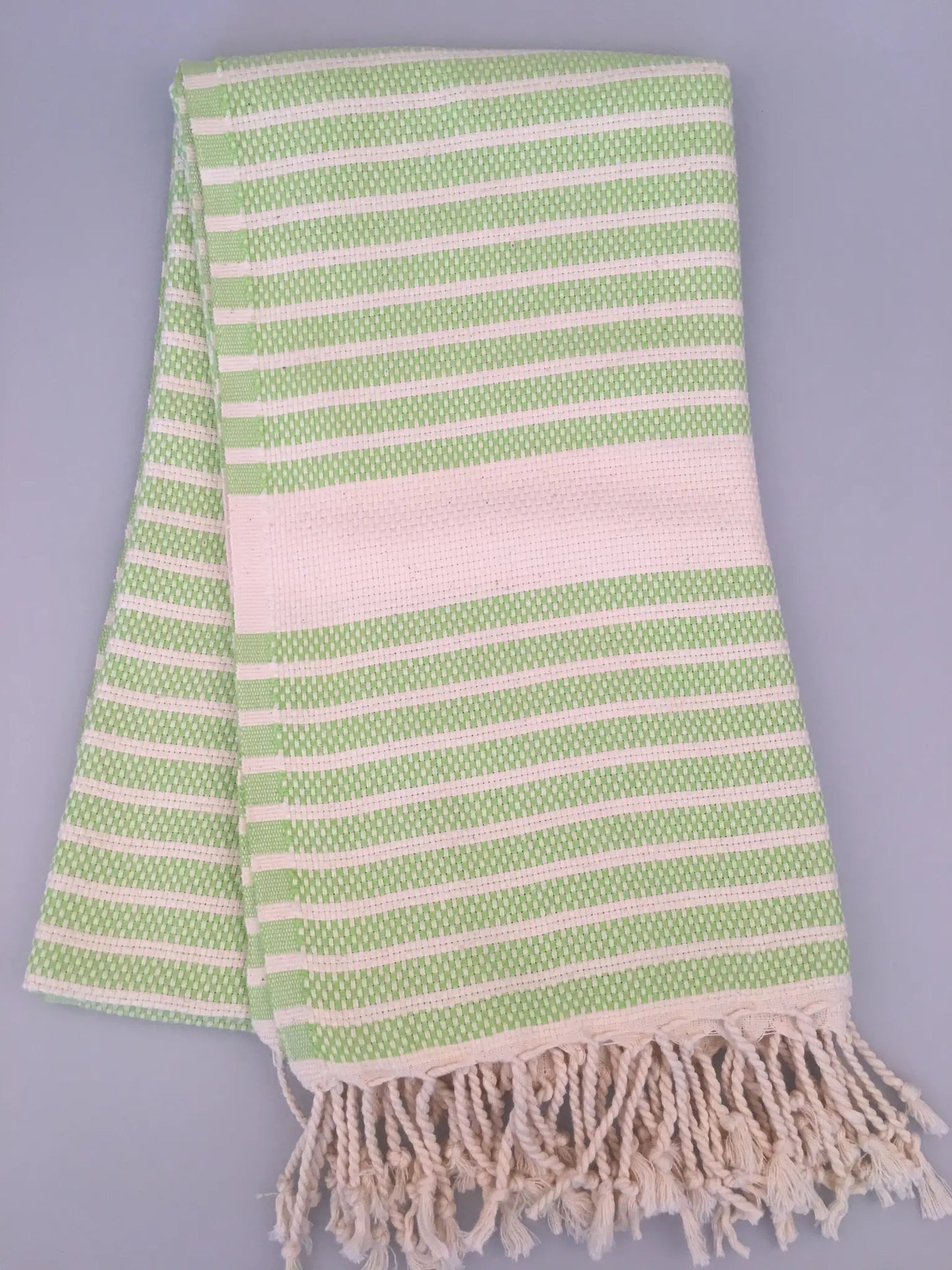 Green and white striped Hittite Turkish towel with fringed edges, folded on a light gray background.