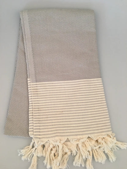 "Gray Miletus Turkish towel peshtemal with a textured pattern and cream-striped hem, fringed edges."