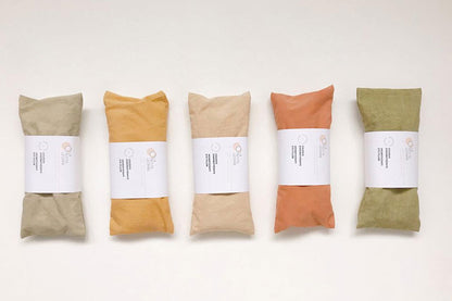 Five wrapped bundles in soft, muted colors—green, beige, orange, and two shades of light green—each secured with a white labe